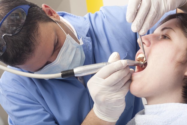 dentist inspecting patient’s teeth at a dental office visit