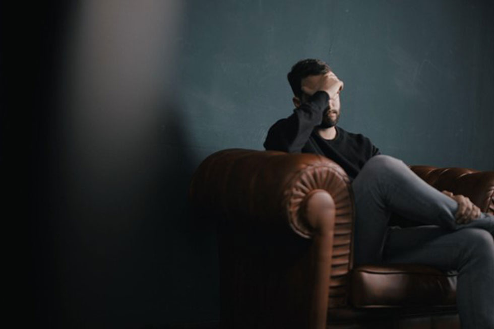 man holding head from exhaustion in need of sleep apnea treatment