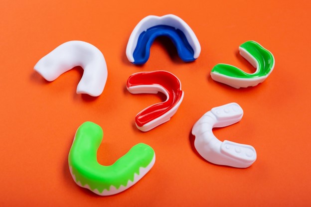 Six dental mouthguards displayed on an orange background
