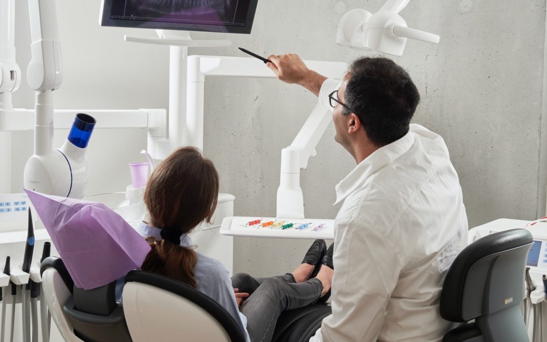Woman in a dental chair reclines as a dentist discusses his findings during a routine checkup in Oakbrook Terrace, IL