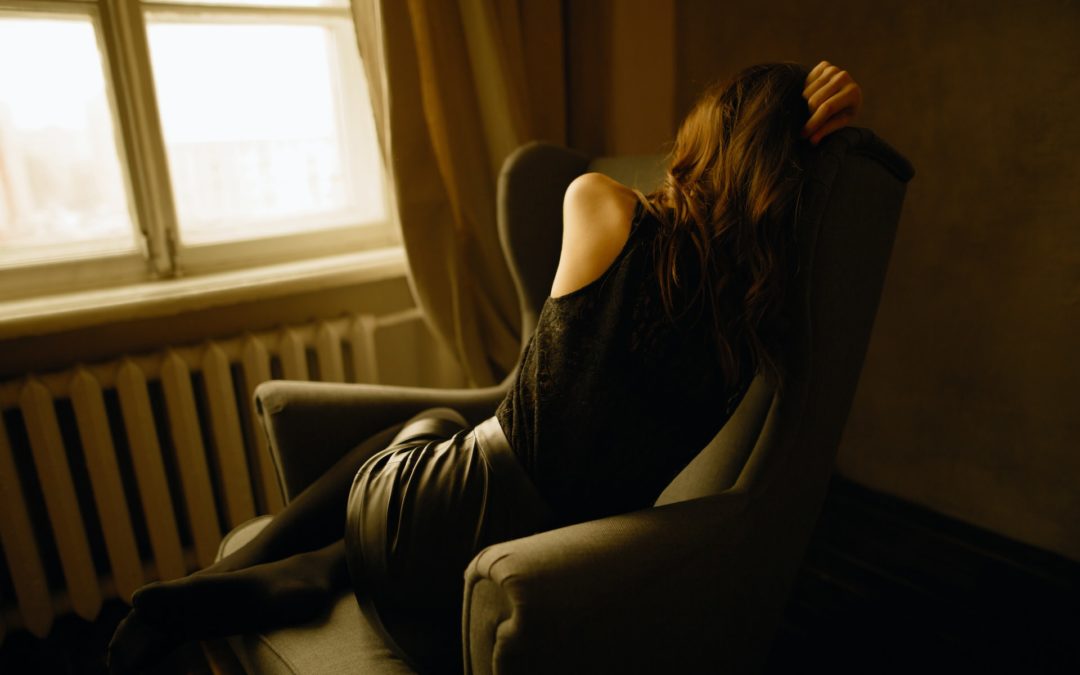 Woman sits with her back to the camera, indicating depression